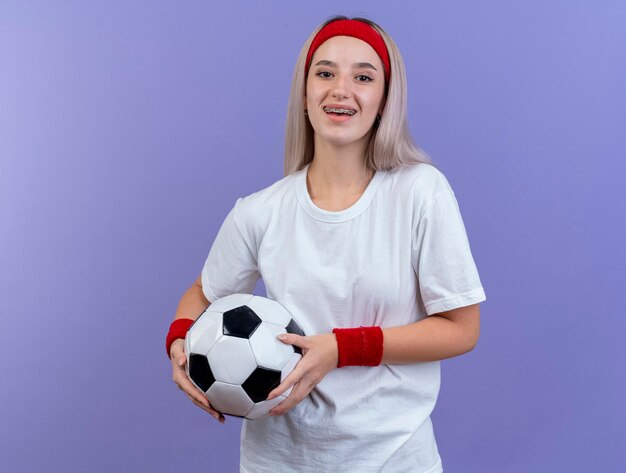 Jovem sorridente caucasiana desportiva com aparelho e faixa na cabeça