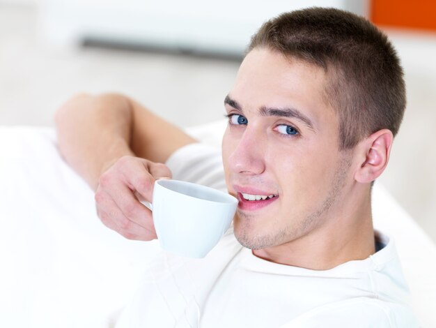 Jovem sorridente com uma xícara de café em casa