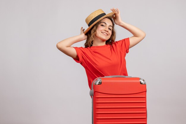 jovem sorridente em pé atrás de sua valise em branco