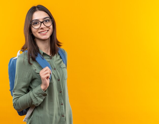 Jovem sorridente, estudante, usando mochila e óculos