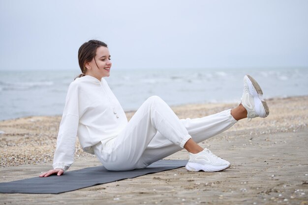 Jovem sorridente fazendo sua meditação na praia Foto de alta qualidade