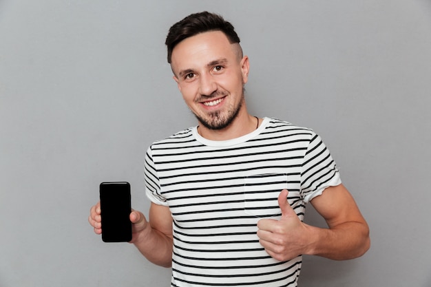 Jovem sorridente mostrando a tela do telefone móvel