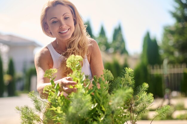 Jovem sorridente no jardim lidando com flores