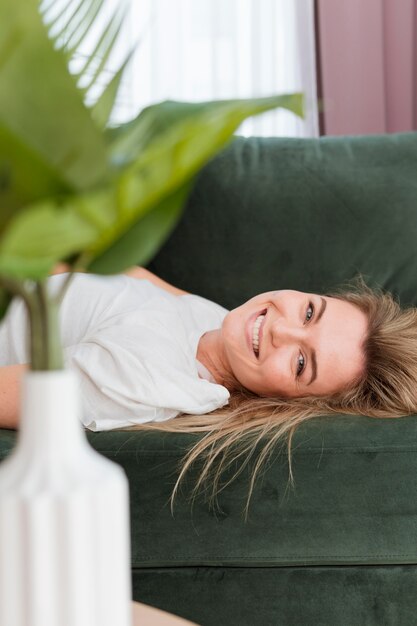 Jovem sorridente relaxando em casa e planta