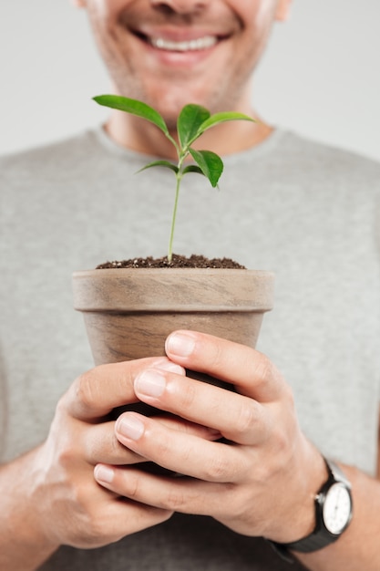 Foto grátis jovem sorridente segurando a planta.