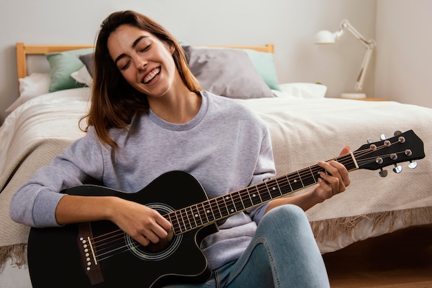 Jovem sorridente tocando violão em casa