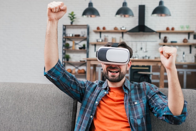 Jovem sorridente usando óculos de realidade virtual cerrando o punho