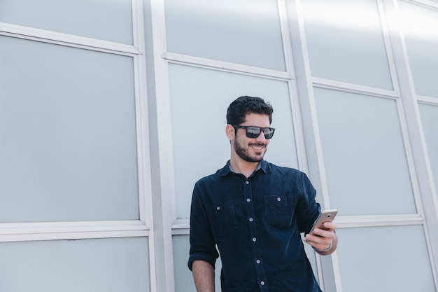 Foto grátis jovem sorridente usando smartphone