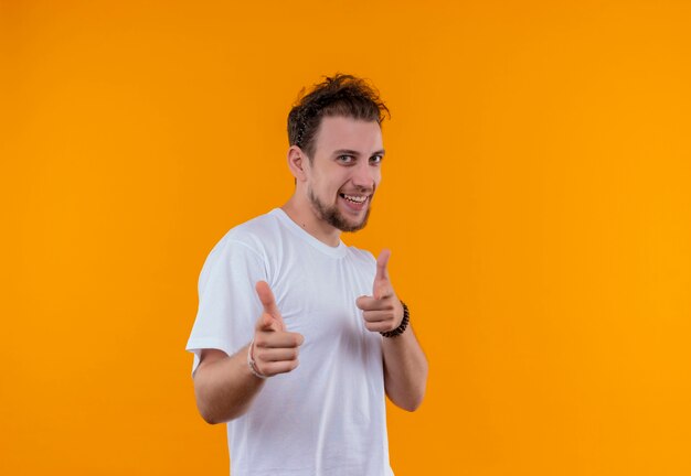 Jovem sorridente, vestindo uma camiseta branca, mostrando seu gesto em um fundo laranja isolado