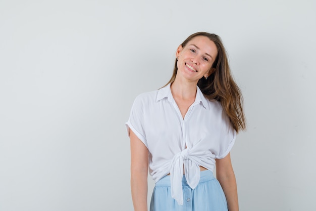 Jovem sorrindo enquanto olha para a frente com blusa, saia e parece positiva