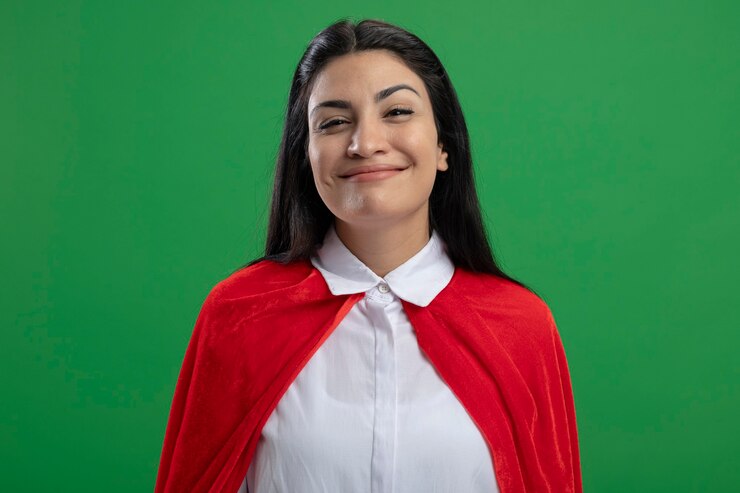 Foto grátis jovem supermulher alegre sorrindo para o público, olhando para a frente, isolada na parede verde