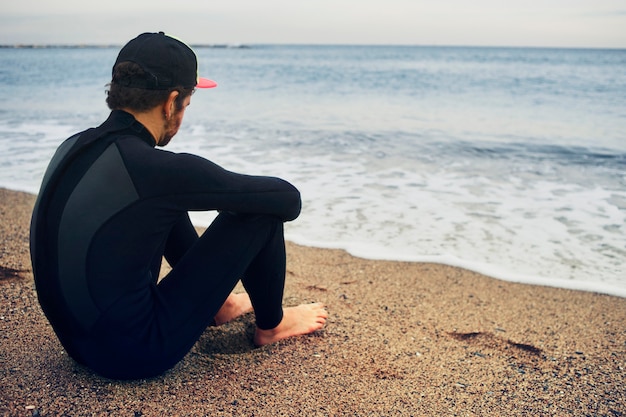 Jovem surfista na praia com boné