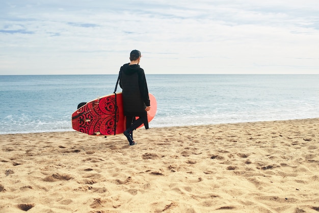 Jovem surfista na praia com prancha de surf