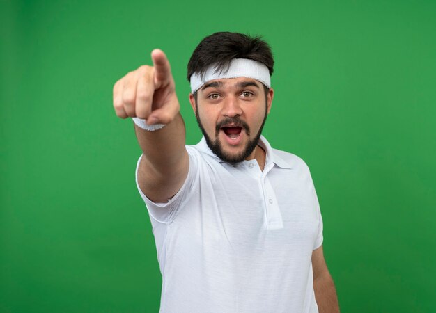 Jovem surpreso e esportivo usando bandana e pulseira mostrando seus gestos