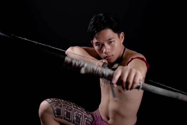 jovem TAILÂNDIA guerreiro masculino posando em uma posição de luta com um arco