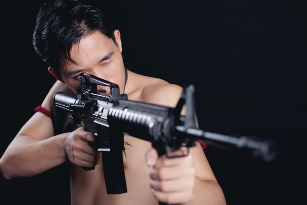 jovem TAILÂNDIA guerreiro masculino posando em uma posição de luta com uma arma de fogo em preto