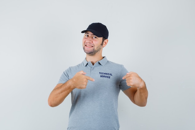 Foto grátis jovem técnico apontando para sua camiseta de uniforme e parecendo orgulhoso.