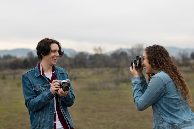 Jovem tirando foto de amigo no campo