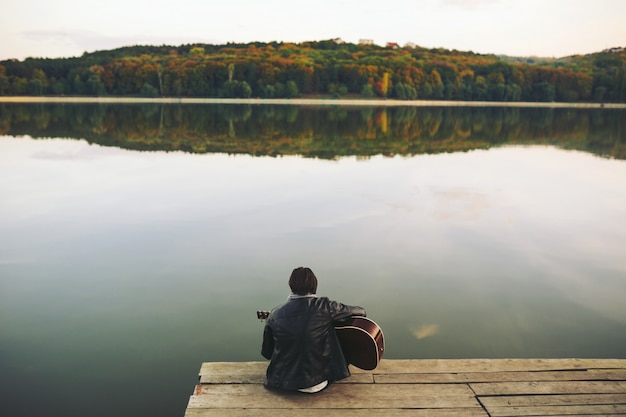 Jovem tocando guitarra no lago