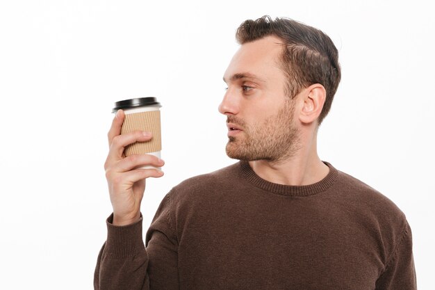 Jovem tomando café. Olhando de lado.