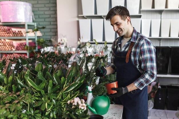 Jovem trabalhador com avental azul na floricultura