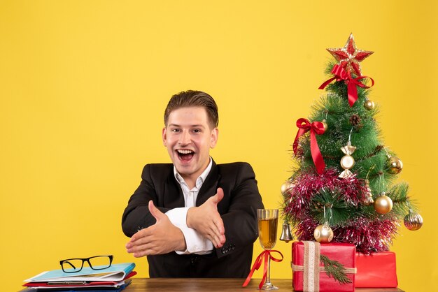 Jovem trabalhador do sexo masculino sentado com uma árvore e presentes de Natal