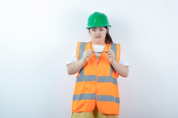 Jovem trabalhadora da construção civil usando óculos sobre uma parede branca