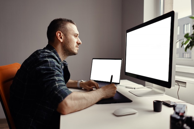 Jovem, trabalhando com computador e monitor interativo com caneta