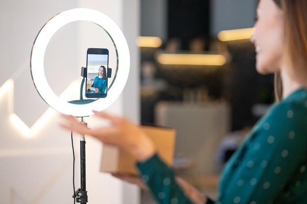 Foto grátis jovem treinador de beleza sorridente apresentando novos produtos de beleza para o público online