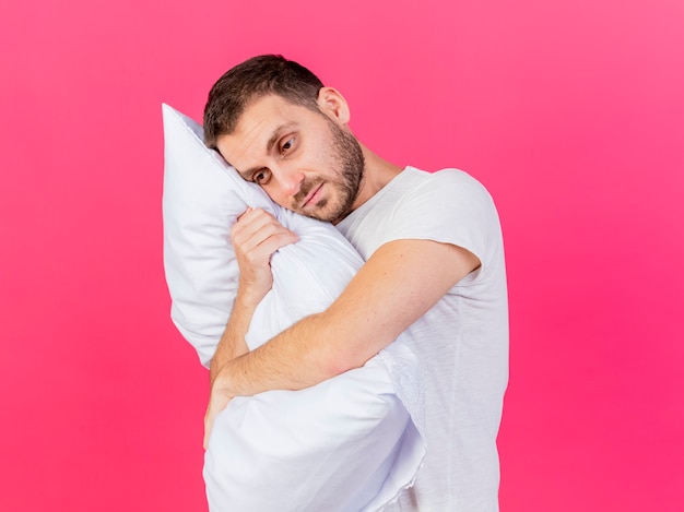 Jovem triste abraçando o travesseiro isolado no fundo rosa