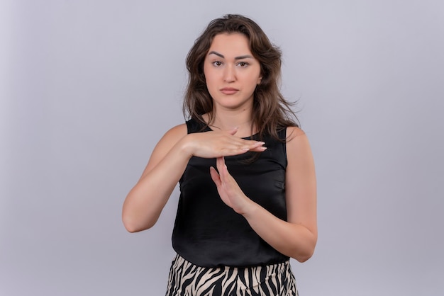 Jovem triste vestindo camiseta preta mostrando gesto de tempo limite na parede branca