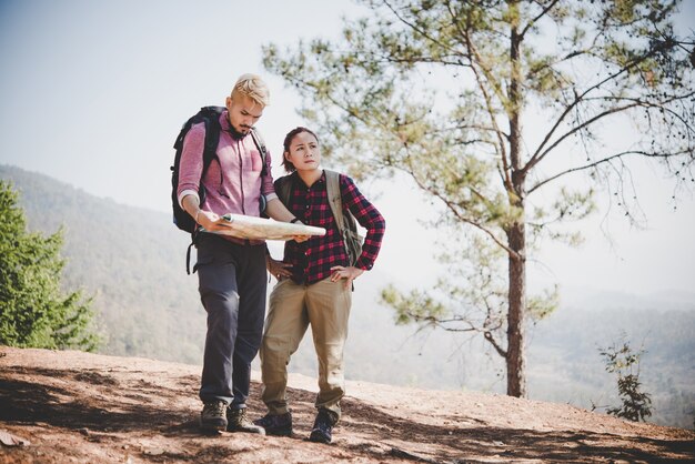 Jovem turista viajando nos feriados na montanha olhando o mapa em busca de atrações. Conceito de viagem.