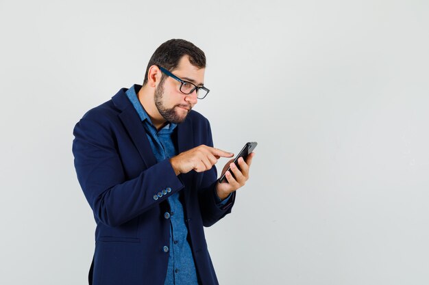 Jovem usando o celular em uma camisa, jaqueta e parecendo ocupado