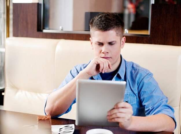 Jovem usando tablet em cafeteria