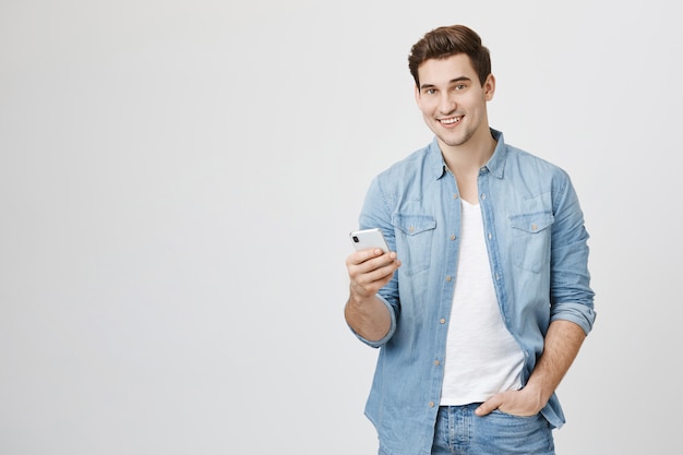 Jovem usando telefone celular, trocando mensagens com um amigo