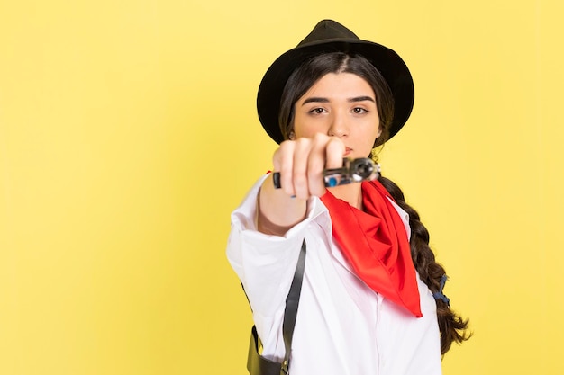 Jovem vaqueira aponta sua arma para a câmera em fundo amarelo foto de alta qualidade