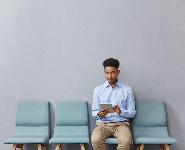 Jovem vestido formalmente sentado na sala de espera