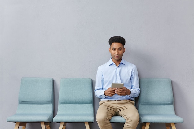 Jovem vestido formalmente sentado na sala de espera