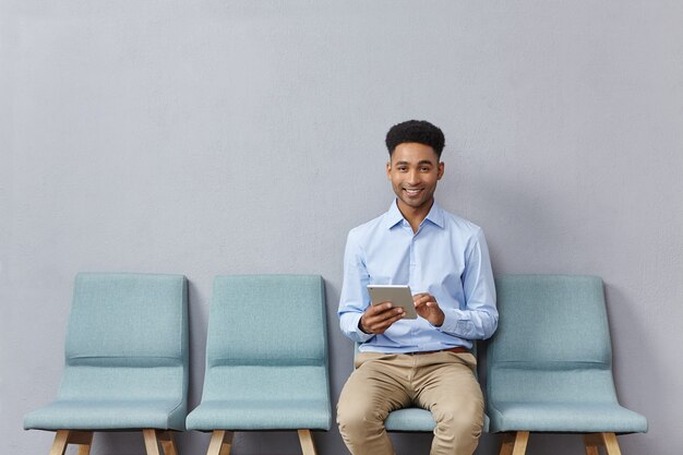 Jovem vestido formalmente sentado na sala de espera