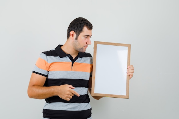 Jovem vestindo camiseta olhando para o quadro em branco e olhando para o foco