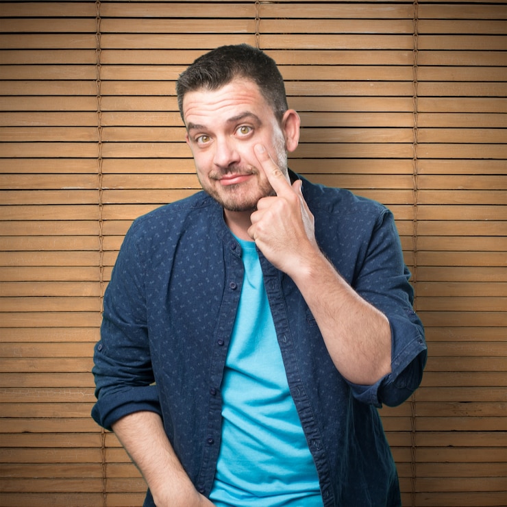 Foto grátis jovem vestindo uma roupa azul. apontando para seu olho.