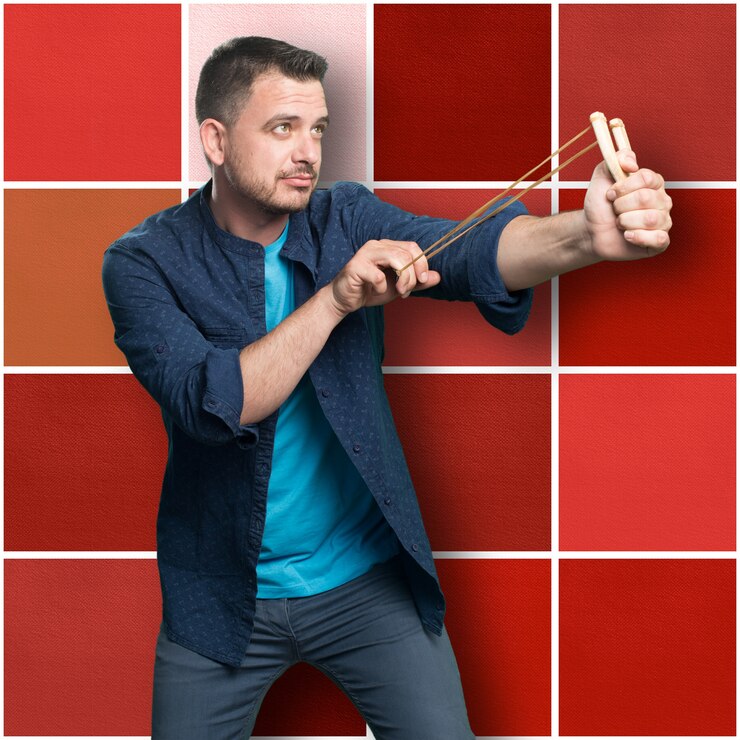 Foto grátis jovem vestindo uma roupa azul. usando um estilingue. pointong para