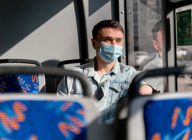 Jovem viajando de ônibus urbano usando máscara cirúrgica