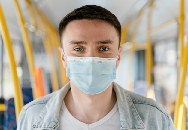 Foto grátis jovem viajando de ônibus urbano usando máscara cirúrgica