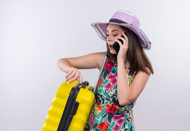 Foto grátis jovem viajante caucasiana falando ao telefone com uma mala no fundo branco isolado