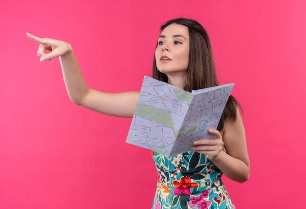 Jovem viajante caucasiana segurando mapa em fundo rosa isolado