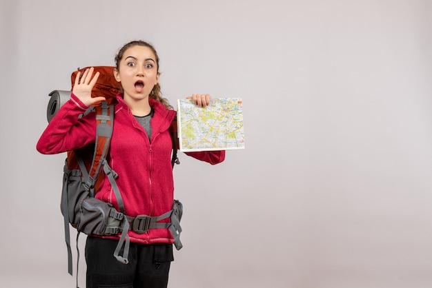 Jovem viajante com uma grande mochila segurando o mapa e acenando com a mão