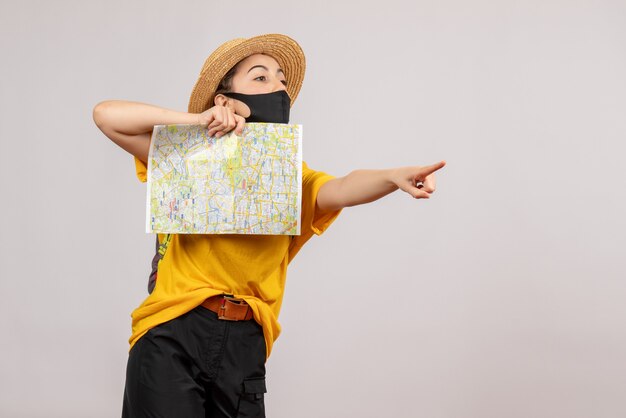 Jovem viajante com uma mochila segurando um mapa apontando para algo de frente