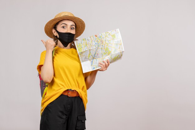 Jovem viajante com uma mochila segurando um mapa apontando para trás