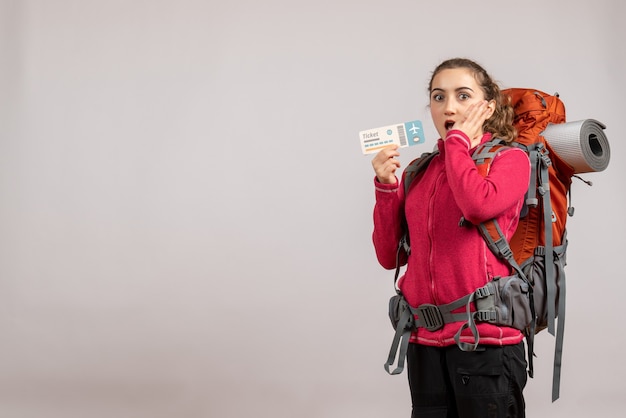 Jovem viajante surpreso com uma grande mochila segurando uma passagem